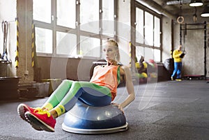 Beautiful sport woman exercising on balance ball in gym. Routine workout for woman& x27;s physical and mental health.