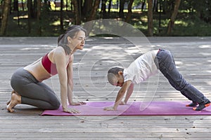 Beautiful sportive mom and little son do yoga in the morning park