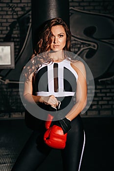 Beautiful sportive woman with dark hair in elegant sportive suit is training in gym
