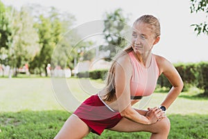 beautiful sportive woman with long hair doing stretching in the park before jogging