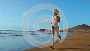 Beautiful sportive woman running along beautiful sandy beach, healthy lifestyle, enjoying active summer vacation near