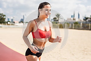 Beautiful sportive woman running while listen music along beautiful sandy beach. Healthy lifestyle, enjoying active summer