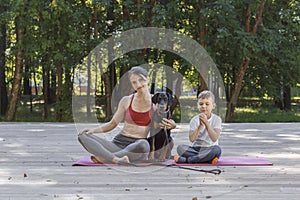 Beautiful sportive woman hugs cute doberman puppy at yoga class in the park