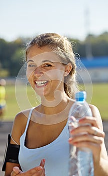 Beautiful sportsgirl in a stadium. Woman with bootle of water. photo