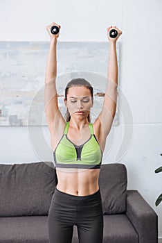 Beautiful sportswoman exercising with dumbbells