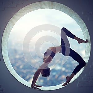 Beautiful sporty fit yogi woman practices yoga asana Eka Pada Urdhva Dhanurasana in a round window