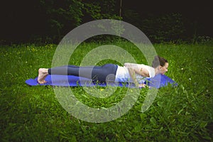 Beautiful sporty fit young woman in sportswear working out outdoors on summer day, doing push-ups, chaturanga dandasana