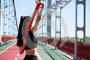 Beautiful sporty girl doing training with rubber resistance band