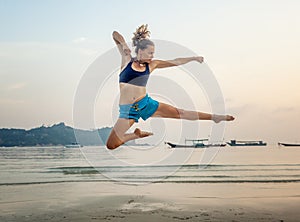 Beautiful sporty girl jumping on the beach against the sea