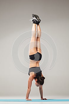 Beautiful sporty girl standing in acrobat pose or yoga asana