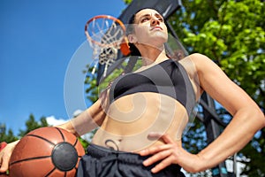 Beautiful, sporty latin girl with a basketball under the ring on a street basketball court. Sport motivation, healthy