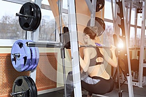 Beautiful sporty woman doing squat workout in gym