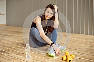 Beautiful sporty woman with bottle of water after doing fitness exercises at gym.