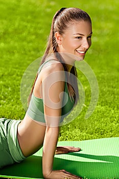 A beautiful sporty woman doing stretching exercise against natu