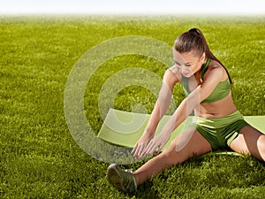 A beautiful sporty woman doing stretching exercise against natu