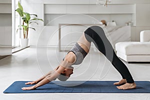 Beautiful sporty woman doing yoga down dog split pose at home