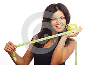 Beautiful sporty woman with green apple and measuring tape