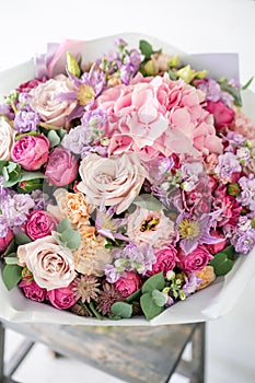 Beautiful spring bouquet. flowers arrangement with various of colors in glass vase on old table. bright room, white wall