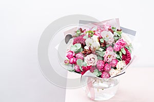 Beautiful spring bouquet. flowers arrangement with various of colors in glass vase on pink table. bright room, white