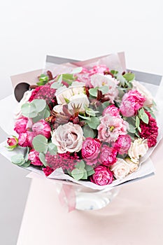 Beautiful spring bouquet. flowers arrangement with various of colors in glass vase on pink table. bright room, white