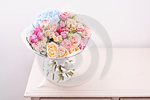 Beautiful spring bouquet. flowers arrangement with various of colors in glass vase on pink table. bright room, white