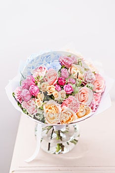 Beautiful spring bouquet. flowers arrangement with various of colors in glass vase on pink table. bright room, white