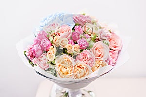 Beautiful spring bouquet. flowers arrangement with various of colors in glass vase on pink table. bright room, white