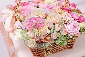 Flowers arrangement with various of colors in wicker basket on pink table. beautiful spring bouquet. bright room, white