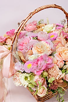 Flowers arrangement with various of colors in wicker basket on pink table. beautiful spring bouquet. bright room, white