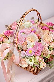 Flowers arrangement with various of colors in wicker basket on pink table. beautiful spring bouquet. bright room, white