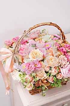 Flowers arrangement with various of colors in wicker basket on pink table. beautiful spring bouquet. bright room, white