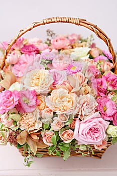 Flowers arrangement with various of colors in wicker basket on pink table. beautiful spring bouquet. bright room, white