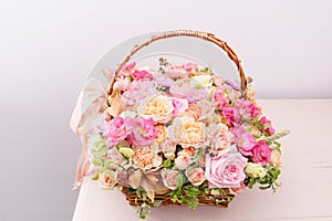 Flowers arrangement with various of colors in wicker basket on pink table. beautiful spring bouquet. bright room, white