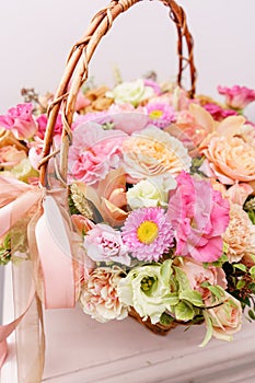 Flowers arrangement with various of colors in wicker basket on pink table. beautiful spring bouquet. bright room, white