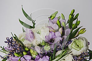 Beautiful spring bouquet of wedding flowers buttercup ranunculus, fresia, lavender in vase with violet tape. Pastel