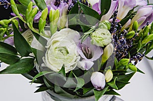 Beautiful spring bouquet of wedding flowers buttercup ranunculus, fresia, lavender in vase with violet tape. Pastel