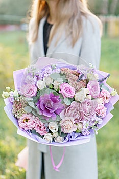 Beautiful spring bouquet. Young girl holding a flowers arrangement with various of colors. Bright dawn or sunset sun