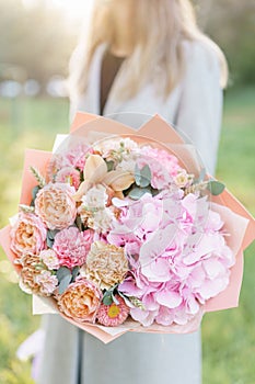 Beautiful spring bouquet. Young girl holding a flowers arrangement with various of colors. Bright dawn or sunset sun