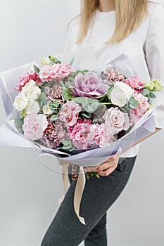 Beautiful spring bouquet. Young girl holding a flowers arrangements with various of colors. white wall.