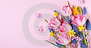 Beautiful spring flowers on pastel pink table top view. Greeting card or banner for International Women Day. Flat lay