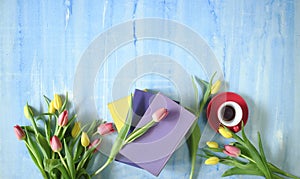 beautiful spring flowers, row of colorful tulips flowers with books and cup of coffee on blue background, concept, flat lay,