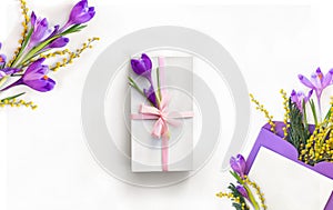 Beautiful spring flowers violet crocuses and yellow flowers mimosa in postal envelope with blank sheet and white gift box