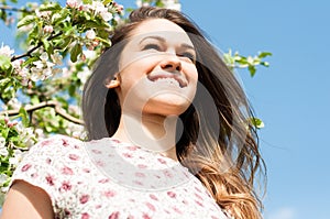 Beautiful spring girl in blooming tree relaxing outside in nature