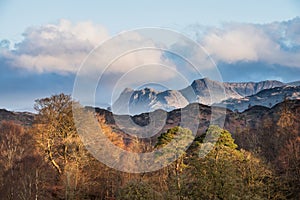 Beautiful Spring landscape image in Lake District looking towards Langdale Pikes during colorful sunset