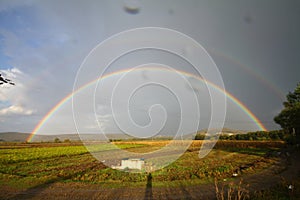 Beautiful spring landscape panorama with a field and a rainbow above it. double rainbow shines in the sky, panoramic view