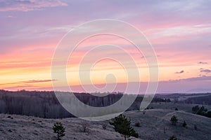 Beautiful spring landscape: sunset, trees, forest, mountains, hills, fields, meadows and sky. Gorgeous, red sky with heavy clouds