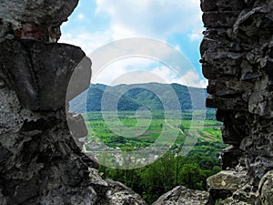Beautiful spring mountain landscape of Khust through a hole in the stone wall of an ancient castle