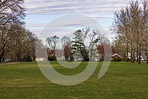 A beautiful spring view of one of the streets in New Jersey, lined with villas adjacent to a park with lush green lawns.