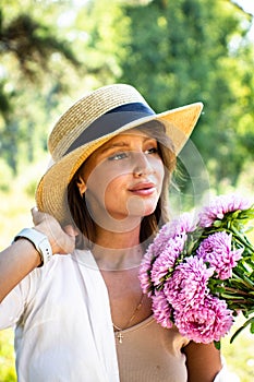 Beautiful spring woman portrait. Woman in a straw hat and a bouquet of flowers