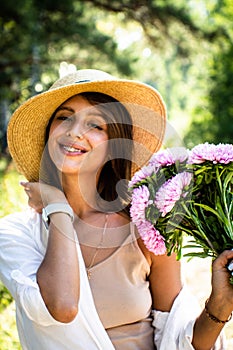 Beautiful spring woman portrait. Woman in a straw hat and a bouquet of flowers